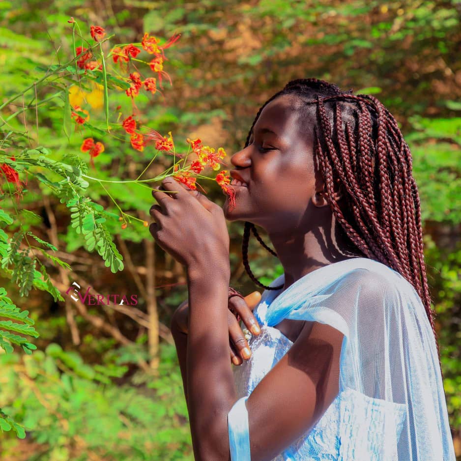 youngster smells flowers with beautiful African hairstyle
