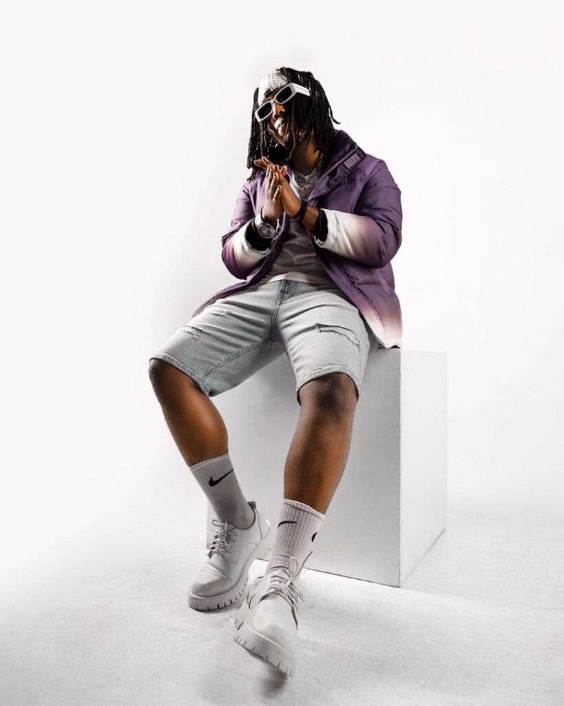Zagazillions wears a purple jacket and white short with white shoes and socks
