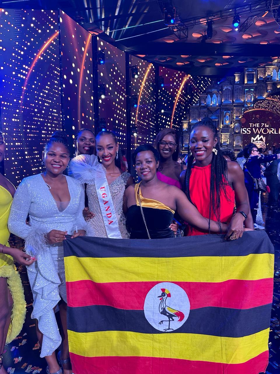 Miss world contestant and her team holding Uganda flag