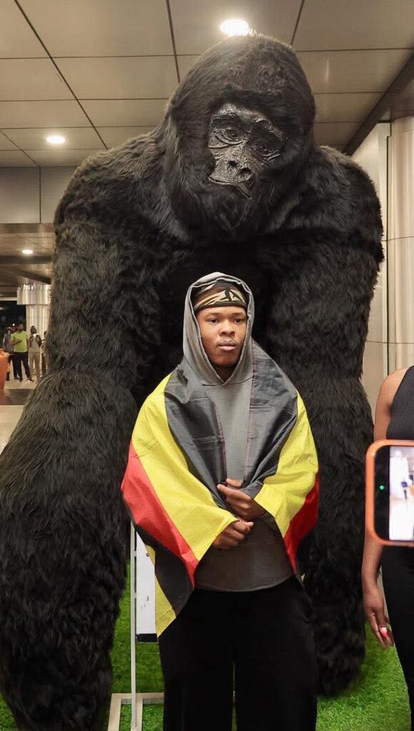 Nasty C posing infront of a gorilla sculpture at Entebbe international airport